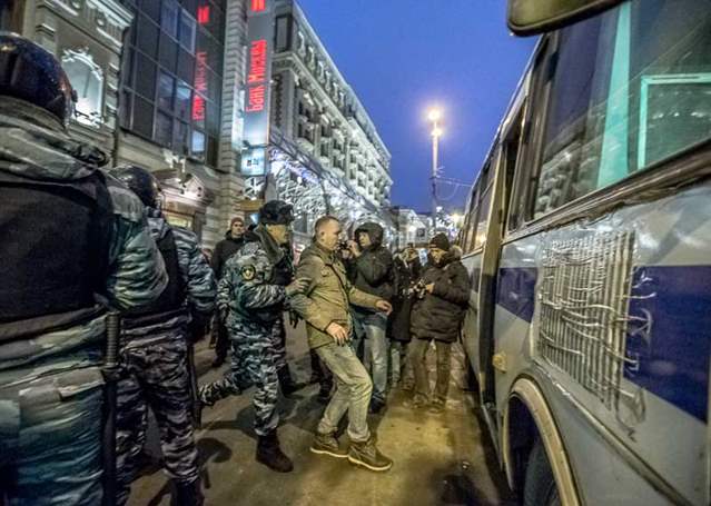 A group of police restrain a man and load him into a police vehicle 